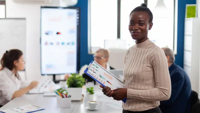 Afrikansk smilende kvinne som viser resultatdokumenter