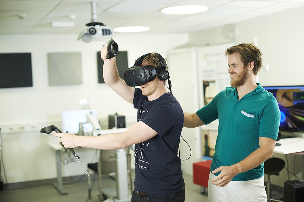 Bildet viser en behandler sammen med en pasient med VR-briller