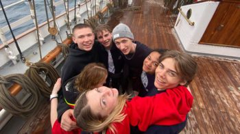 En gjeng med glade ungdommer på dekk på seilskuta Christian Radich