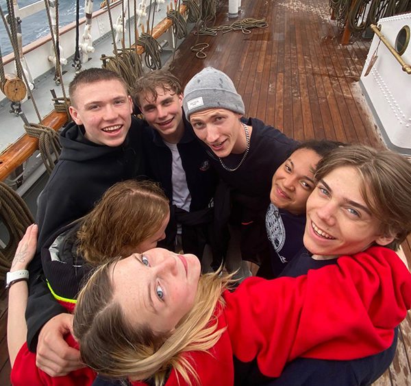 En gjeng med glade ungdommer på dekk på seilskuta Christian Radich
