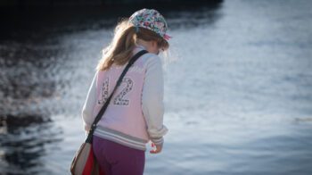 Ensom jente med ryggen til kamera og lutende rygg